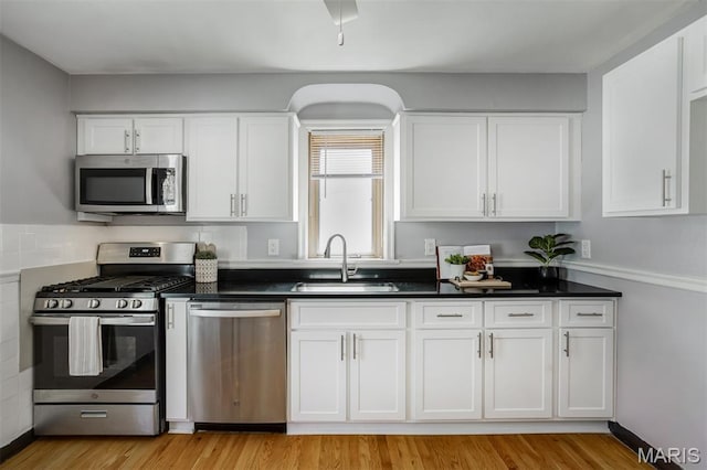 7041 Plainview Ave, Saint Louis, MO 63109 - kitchen featuring stainless steel appliances, white cabinetry, dark countertops, and light wood-style flooring