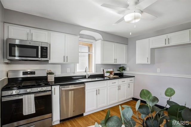 7041 Plainview Ave, Saint Louis, MO 63109 - kitchen with stainless steel appliances, white cabinets, dark countertops, and light wood-style floors
