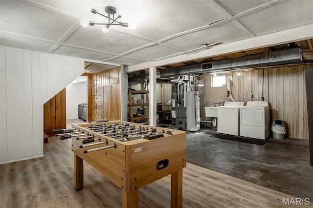 7041 Plainview Ave, Saint Louis, MO 63109 - recreation room with separate washer and dryer, wooden walls, gas water heater, and wood finished floors