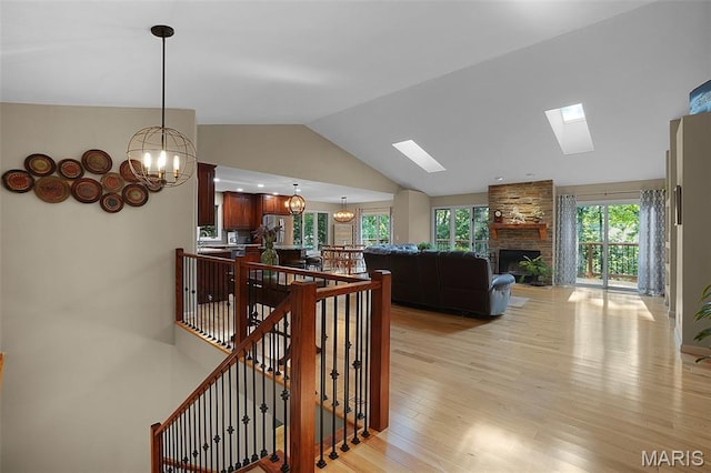 877 Red Fox Dr, Innsbrook, MO 63390 - stairs featuring vaulted ceiling, wood finished floors, a stone fireplace, a skylight, and a chandelier