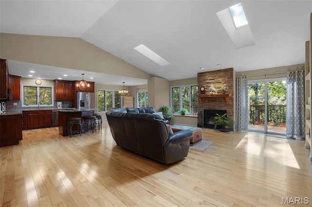 877 Red Fox Dr, Innsbrook, MO 63390 - living area featuring a skylight, light wood-type flooring, a fireplace, plenty of natural light, and high vaulted ceiling