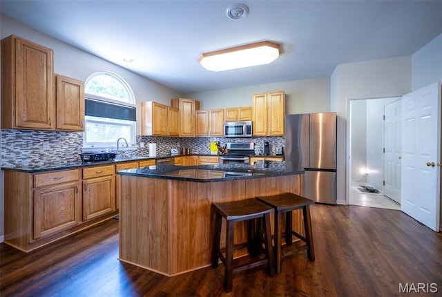 824 Legends View Dr, Eureka, MO 63025 - kitchen featuring appliances with stainless steel finishes, a kitchen breakfast bar, a center island, tasteful backsplash, and dark stone counters