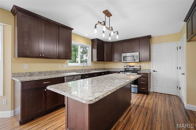 8 Dugout Ct, Ofallon, MO 63366 - kitchen with appliances with stainless steel finishes, wood finished floors, dark brown cabinetry, and light stone counters