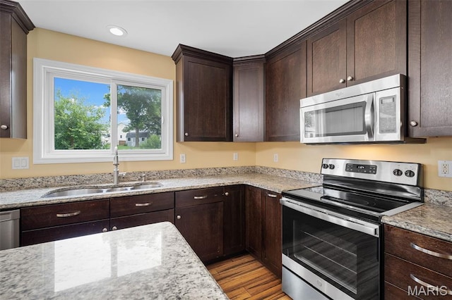 8 Dugout Ct, Ofallon, MO 63366 - kitchen with stainless steel appliances, dark brown cabinets, light wood-style floors, light stone counters, and recessed lighting