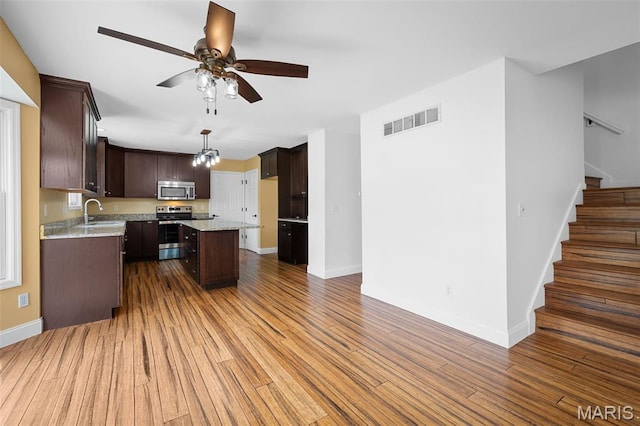 8 Dugout Ct, Ofallon, MO 63366 - kitchen featuring appliances with stainless steel finishes, dark brown cabinets, a center island, and a ceiling fan