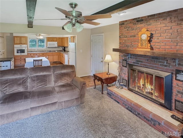 4423 Project Rd, Luebbering, MO 63061 - living area with a brick fireplace, beamed ceiling, a ceiling fan, light carpet, and baseboards