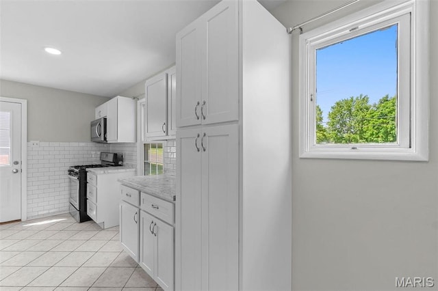2490 Mullanphy Ln, Florissant, MO 63031 - kitchen with appliances with stainless steel finishes, light countertops, healthy amount of natural light, light tile patterned floors, and recessed lighting