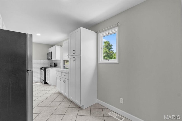 2490 Mullanphy Ln, Florissant, MO 63031 - kitchen with appliances with stainless steel finishes, light tile patterned flooring, light countertops, white cabinets, and tasteful backsplash