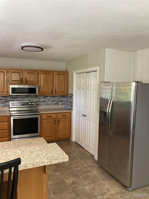 225 Country Crest Ln, Union, MO 63084 - kitchen featuring stainless steel appliances, light countertops, decorative backsplash, and brown cabinets