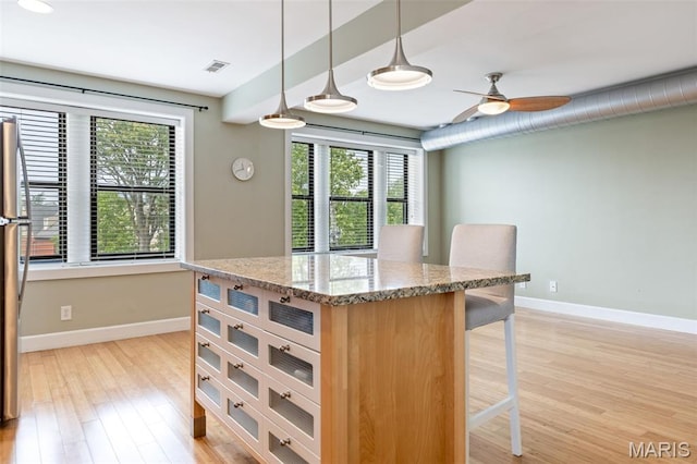 4220 Mcpherson Ave Unit 303, Saint Louis, MO 63108 - kitchen featuring plenty of natural light, a kitchen breakfast bar, light wood finished floors, and a ceiling fan