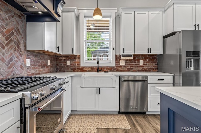 422 N 2nd St, De Soto, MO 63020 - kitchen featuring stainless steel appliances, wall chimney exhaust hood, white cabinets, backsplash, and pendant lighting