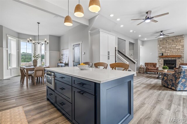 422 N 2nd St, De Soto, MO 63020 - kitchen featuring a ceiling fan, a stone fireplace, wood finished floors, hanging light fixtures, and a center island