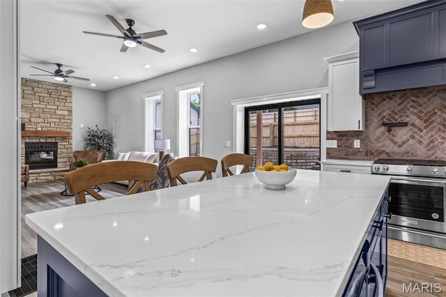 422 N 2nd St, De Soto, MO 63020 - kitchen with stainless steel range oven, a fireplace, tasteful backsplash, a ceiling fan, and a kitchen island