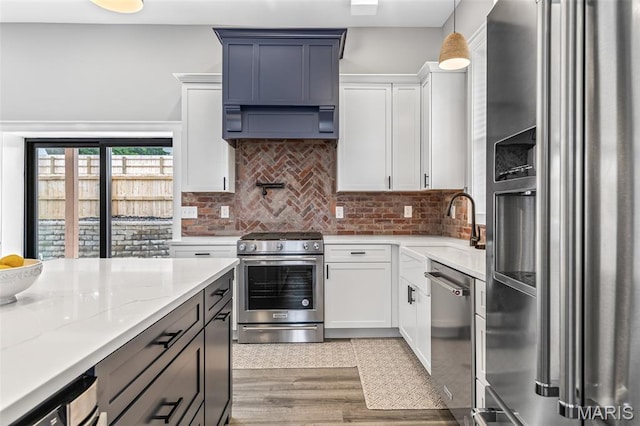 422 N 2nd St, De Soto, MO 63020 - kitchen with appliances with stainless steel finishes, decorative backsplash, white cabinets, ventilation hood, and light stone counters