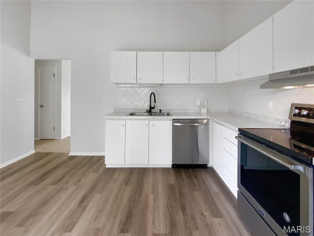 887 Totem Woods Ct, Manchester, MO 63021 - kitchen featuring appliances with stainless steel finishes, under cabinet range hood, light countertops, wood finished floors, and backsplash