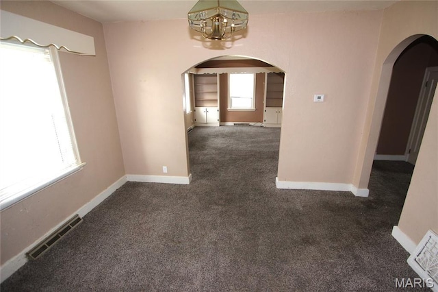 205 Deguire, Fredericktown, MO 63645 - empty room with arched walkways, a chandelier, and dark colored carpet