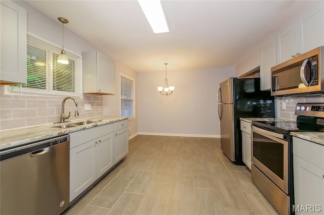 3702 E 106th Ter, Kansas City, MO 64137 - kitchen with stainless steel appliances, tasteful backsplash, a chandelier, and white cabinets
