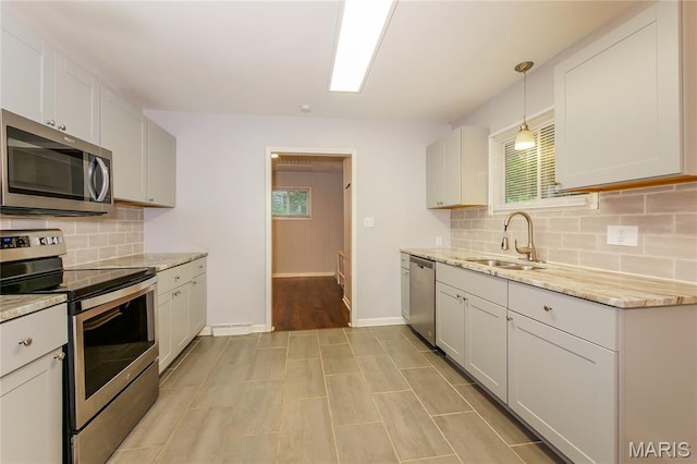 3702 E 106th Ter, Kansas City, MO 64137 - kitchen with stainless steel appliances, healthy amount of natural light, decorative backsplash, and light stone countertops