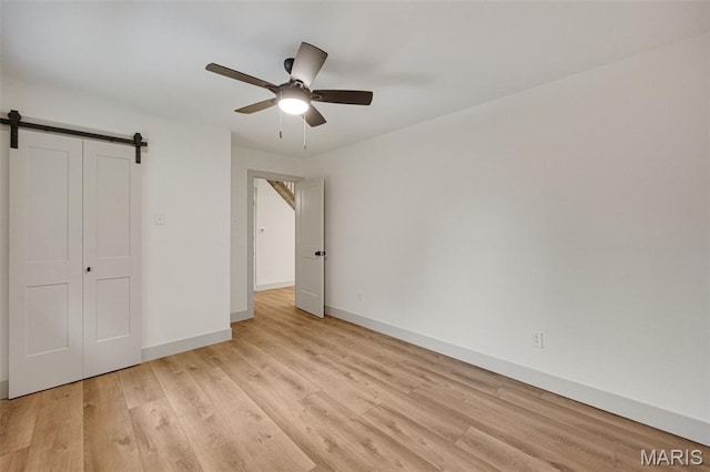 10293 Strange Rd, Potosi, MO 63664 - unfurnished bedroom featuring light wood finished floors, a barn door, ceiling fan, and a closet
