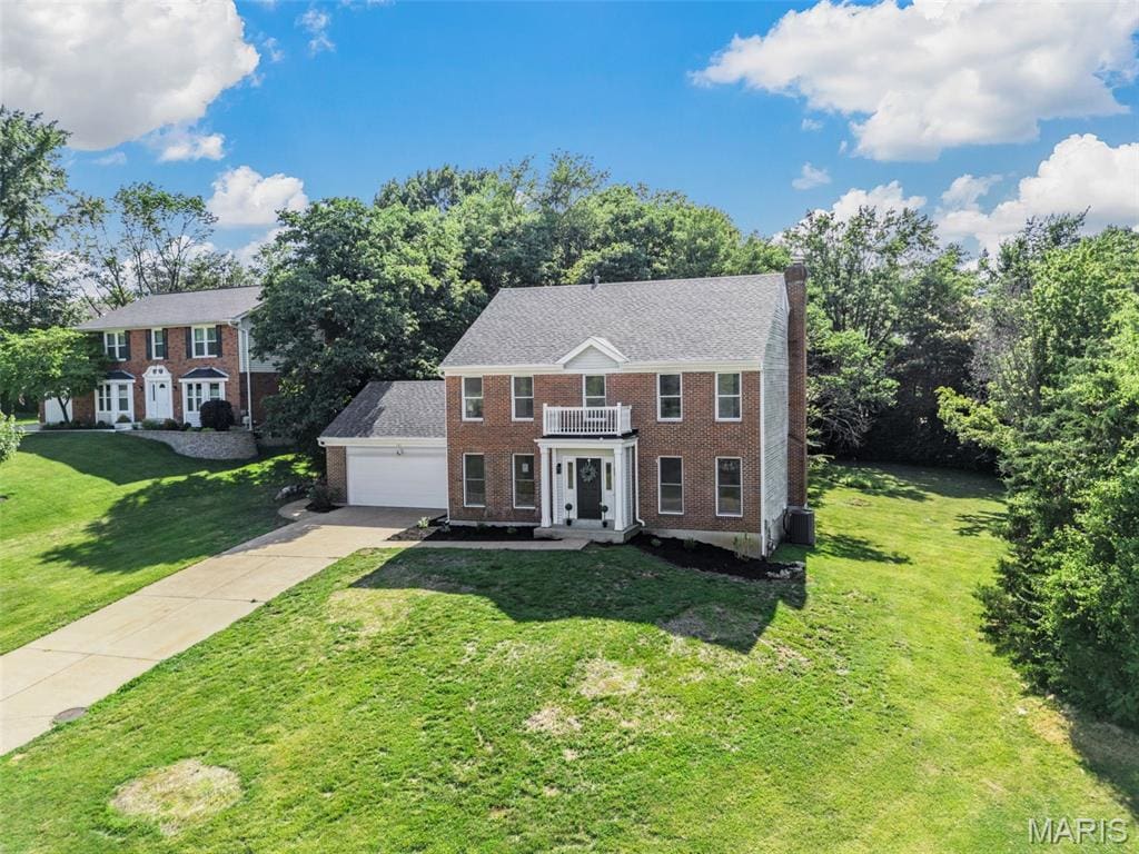 145 White Tree Ln, Ballwin, MO 63011 - view of front facade with a balcony, brick siding, driveway, a chimney, and a front yard