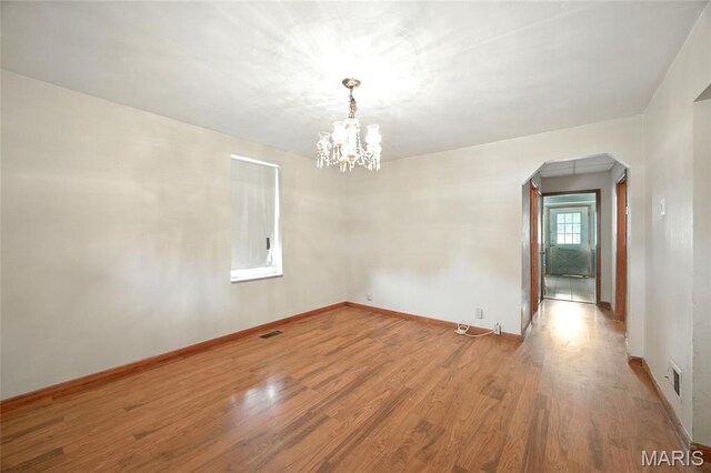4934 Tiemann Ave, Saint Louis, MO 63123 - empty room featuring arched walkways, wood finished floors, and a chandelier