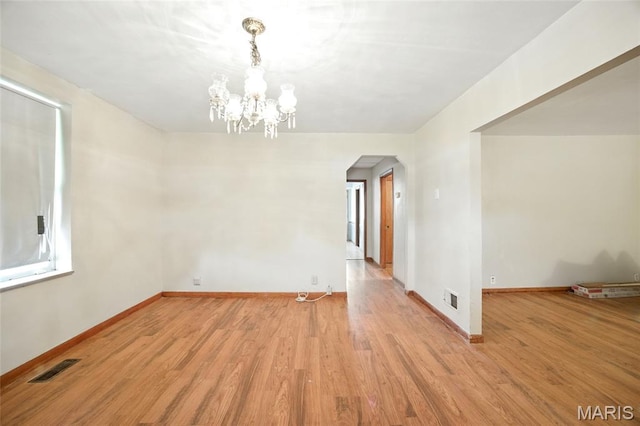 4934 Tiemann Ave, Saint Louis, MO 63123 - spare room with arched walkways, light wood-type flooring, and a chandelier