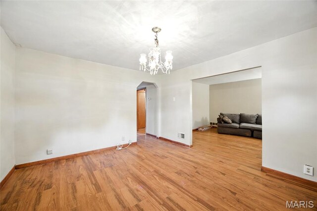 4934 Tiemann Ave, Saint Louis, MO 63123 - unfurnished room featuring arched walkways, wood finished floors, and a chandelier