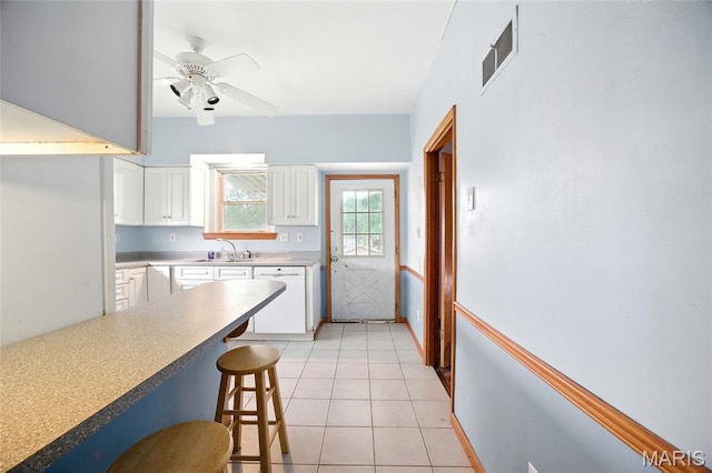4934 Tiemann Ave, Saint Louis, MO 63123 - kitchen with white dishwasher, a breakfast bar area, white cabinetry, ceiling fan, and light countertops