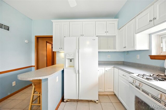 4934 Tiemann Ave, Saint Louis, MO 63123 - kitchen featuring white appliances, white cabinets, light countertops, light tile patterned flooring, and a breakfast bar area