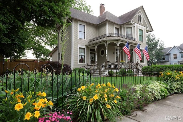 302 N Main St, Saint Elmo, IL 62458 - victorian home with covered porch, a fenced front yard, and a chimney