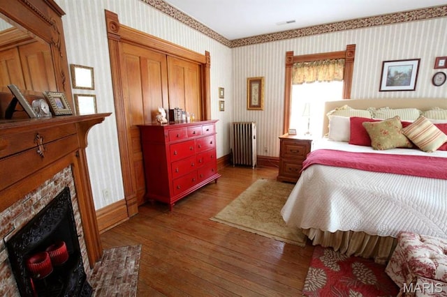 302 N Main St, Saint Elmo, IL 62458 - bedroom with radiator heating unit, wallpapered walls, hardwood / wood-style floors, and a premium fireplace