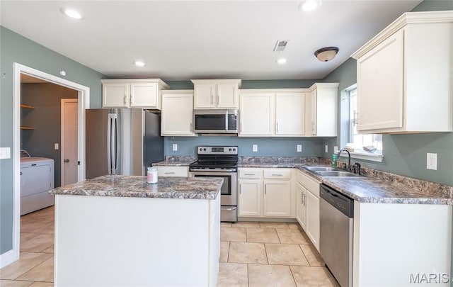 111 Brush Creek Pkwy, Saint Robert, MO 65584 - kitchen with stainless steel appliances, washer / dryer, a center island, white cabinetry, and recessed lighting