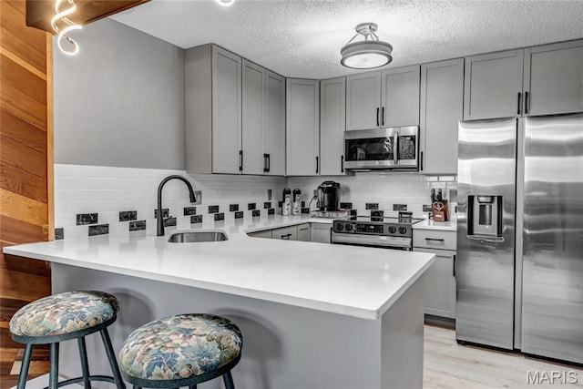 225 Hemingway Ln Unit F, Weldon Spring, MO 63304 - kitchen featuring appliances with stainless steel finishes, gray cabinets, a peninsula, backsplash, and a textured ceiling