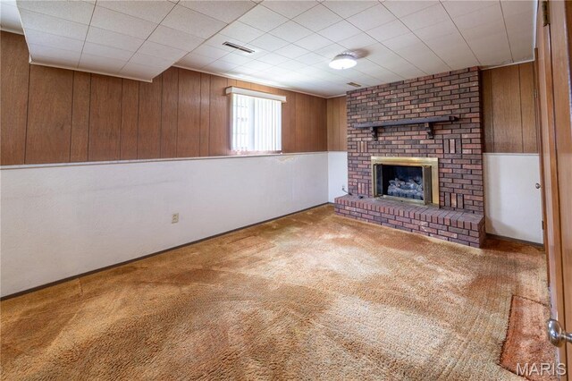 1131 Kimbel Ln, Jackson, MO 63755 - unfurnished living room featuring wooden walls, a brick fireplace, and carpet flooring