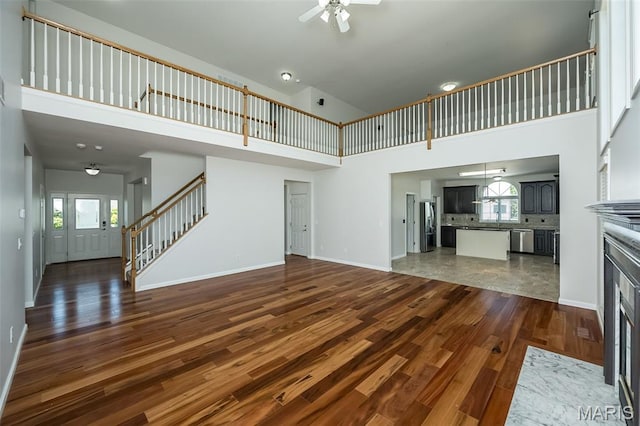 86 Homefield Square Ct, Ofallon, MO 63366 - unfurnished living room with high vaulted ceiling, stairway, a ceiling fan, dark wood-style floors, and a fireplace with flush hearth