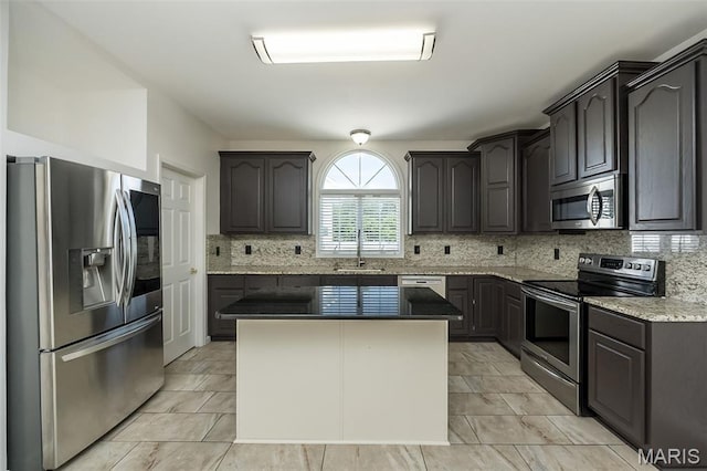 86 Homefield Square Ct, Ofallon, MO 63366 - kitchen with appliances with stainless steel finishes, decorative backsplash, a kitchen island, and light stone countertops