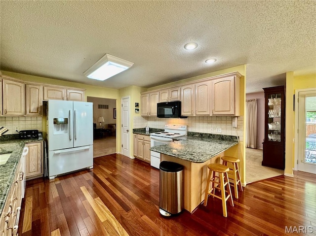 829 Clemson Ave, Fairview Heights, IL 62208 - kitchen with white appliances, dark wood-type flooring, a peninsula, a kitchen breakfast bar, and a textured ceiling