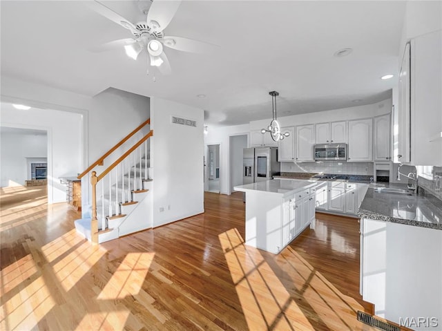 596 Eagle Manor Ln, Chesterfield, MO 63017 - kitchen with stainless steel appliances, white cabinetry, a kitchen island, wood finished floors, and decorative backsplash