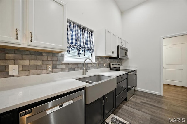 1575 Hickory Lndg, De Soto, MO 63020 - kitchen featuring appliances with stainless steel finishes, white cabinets, light countertops, tasteful backsplash, and a towering ceiling