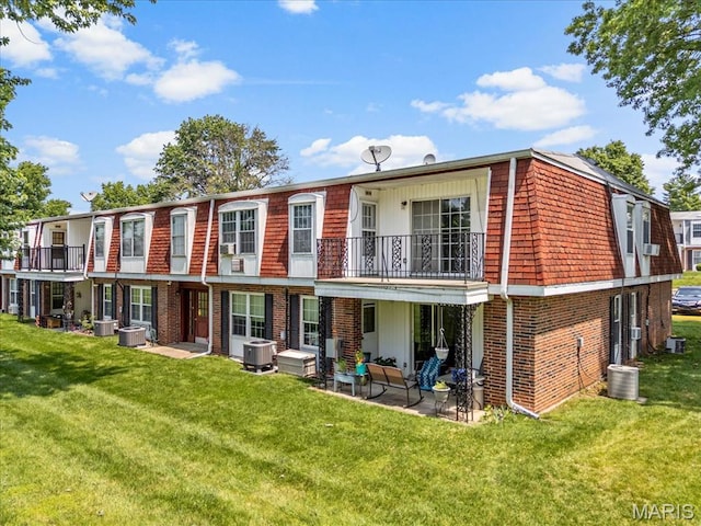 1745 Herault Pl Unit F, Saint Louis, MO 63125 - back of house featuring mansard roof, brick siding, a balcony, and a lawn