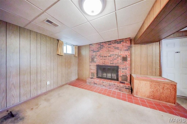 10820 Clayton Ct, Rolla, MO 65401 - unfurnished living room with a brick fireplace, wood walls, a paneled ceiling, and carpet