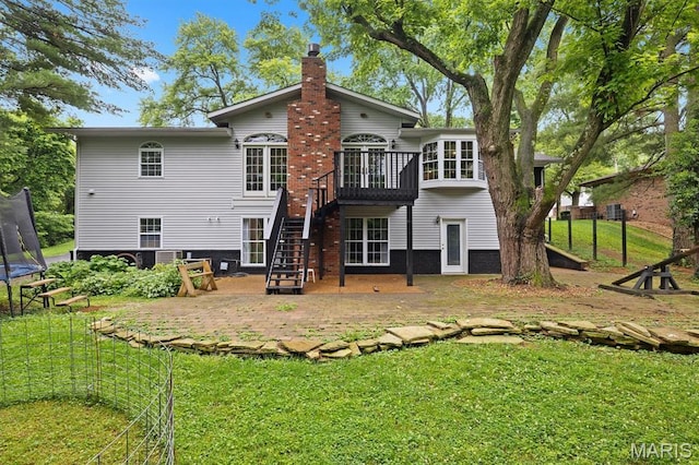 101 E Fairway Dr, Belleville, IL 62223 - back of property with a trampoline, a chimney, stairs, a patio area, and a lawn