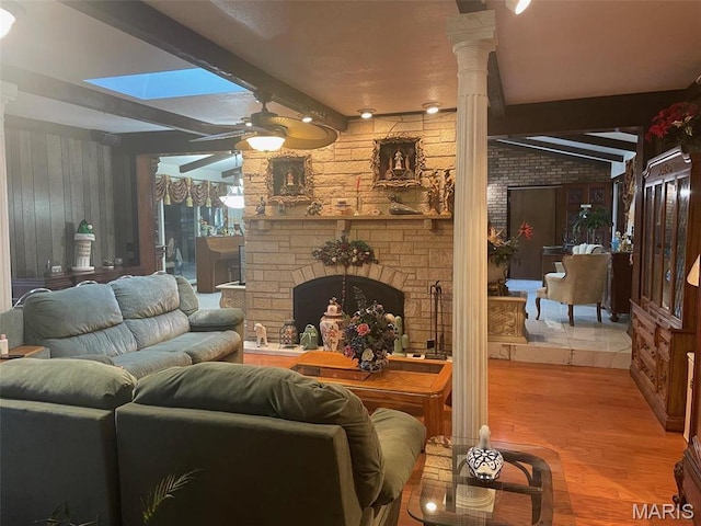 12746 Rolling Hills Dr, Trenton, IL 62293 - living room featuring ornate columns, wood finished floors, a stone fireplace, beam ceiling, and a ceiling fan