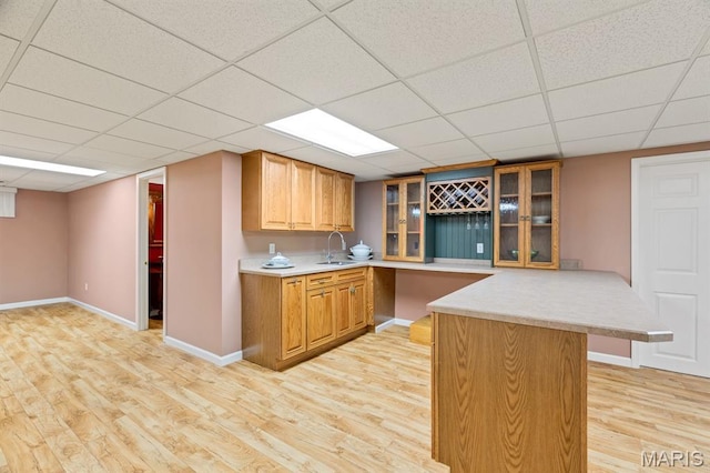 10 Rio Vista Dr, Frontier Township, MO 63303 - kitchen featuring light wood-style floors, a peninsula, glass insert cabinets, light countertops, and a paneled ceiling