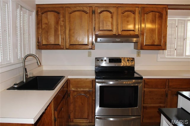 111 W Broadway St, Hayti, MO 63851 - kitchen with stainless steel range with electric cooktop, under cabinet range hood, light countertops, and brown cabinets