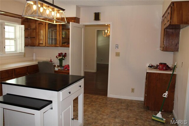 111 W Broadway St, Hayti, MO 63851 - kitchen featuring a chandelier, brown cabinets, dark countertops, glass insert cabinets, and pendant lighting