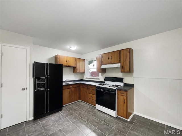 5031 Tulip Tree Ln, Hazelwood, MO 63042 - kitchen featuring black refrigerator with ice dispenser, gas stove, under cabinet range hood, dark countertops, and brown cabinets