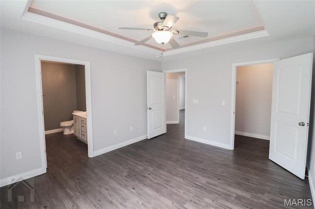 278 Settlers Pass, Waynesville, MO 65583 - unfurnished bedroom featuring a tray ceiling, dark wood-type flooring, a spacious closet, and ensuite bathroom