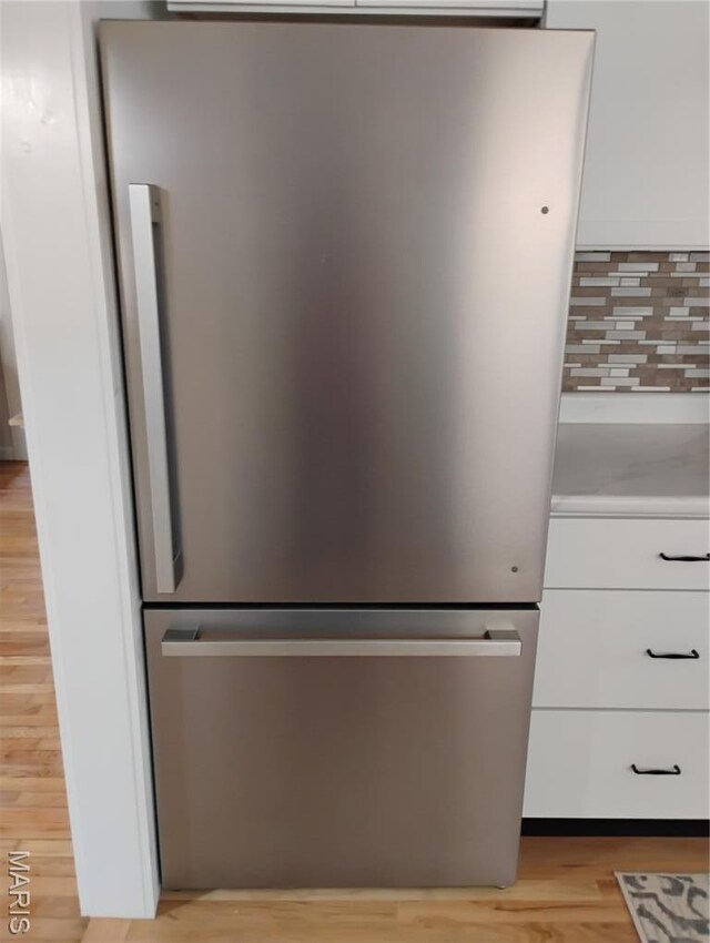 131 Sackett St, Licking, MO 65542 - kitchen view of freestanding refrigerator, white cabinets, backsplash, and light wood-style flooring