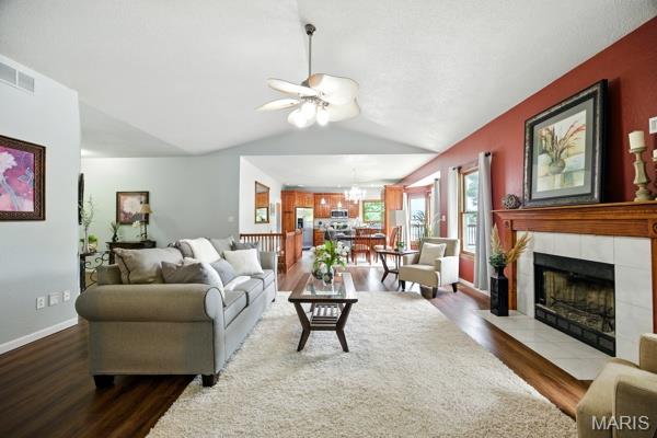 5 Sherman Ct, Hillsboro, MO 63050 - living room featuring wood finished floors, ceiling fan, a tile fireplace, vaulted ceiling, and a chandelier